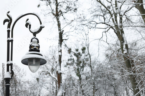 Beautiful street light with snow against sky in winter, space for text