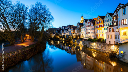 Panoramic view of illuminated historic facades of old town of Tuebingen on Neckar River in southern Germany. Winter evening twilight with colorful reflections, Hölderlin tower and church. Blue hour.