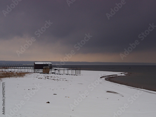 Late fall. Snowy coast. Pier. Big river. Thunder Sky.
