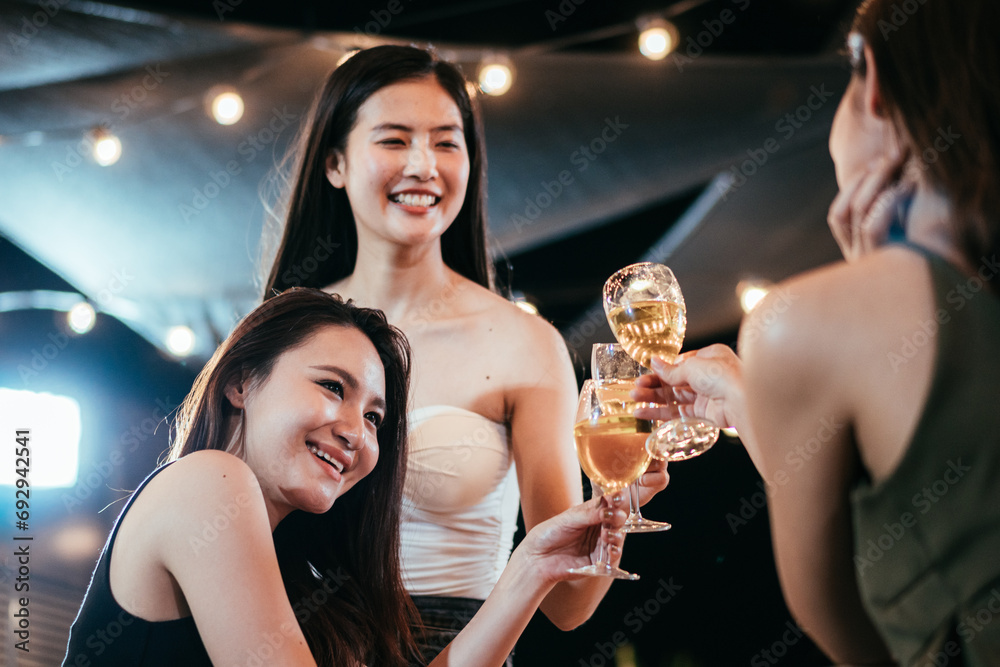 Group of Asian friends smiling and toasting glass of wine together to celebration at the party. Congratulations on success achievement. People hangout on weekend night.