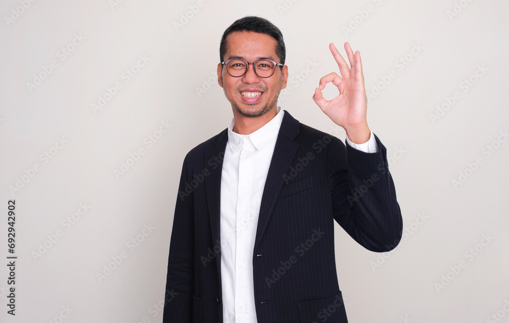 Asian businessman smiling confident and giving OK sign Asian businessman smiling confident and giving OK sign