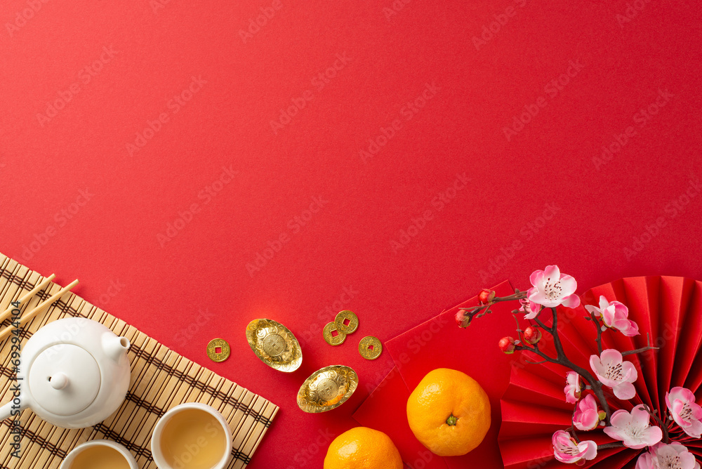 Chinese New Year Banquet Scene: Overhead shot featuring fan, tea ceremony items, bamboo placemat, traditional coins, sycee, Hong Bao, tangerines, sakura on red background. Ideal for festive promo