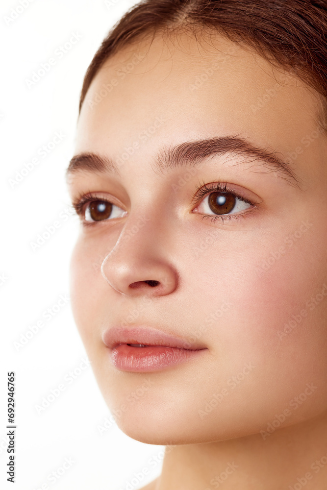 Close-up portrait of beautiful young girl with smooth, healthy, well-kept skin, brown eyes standing against white background. Concept of natural female beauty, skin care, cosmetology and cosmetics Close-up portrait of beautiful young girl with smooth, healthy, well-kept skin, brown eyes standing against white background. Concept of natural female beauty, skin care, cosmetology and cosmetics
