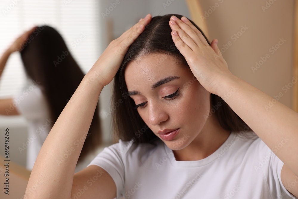 Naklejka premium Woman examining her hair and scalp indoors