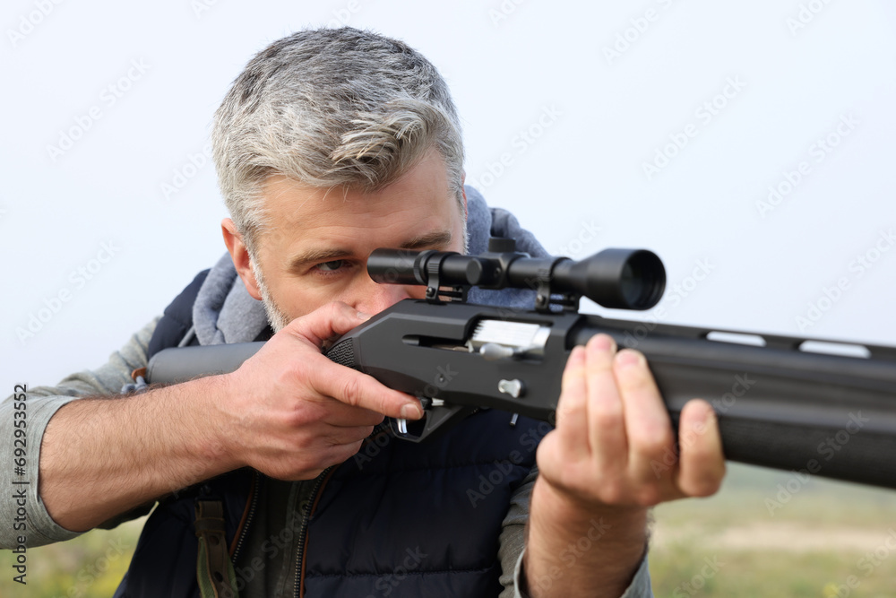 Man aiming with hunting rifle outdoors, closeup Man aiming with hunting rifle outdoors, closeup