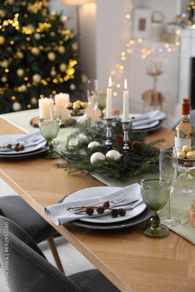 Christmas table setting with festive decor and dishware in room Christmas table setting with festive decor and dishware in room