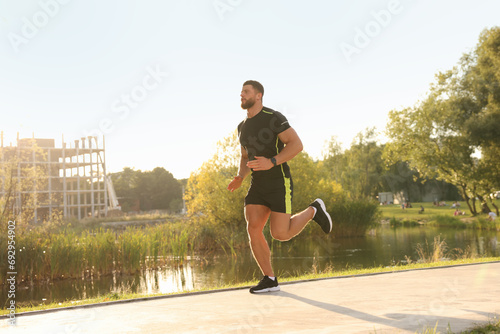 Young man running near pond in park