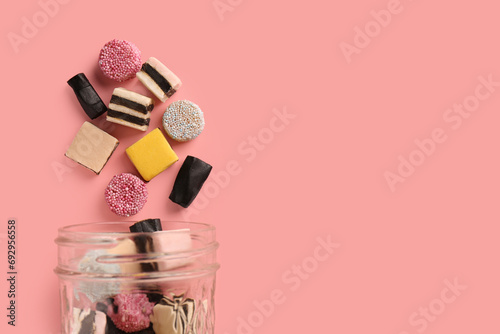 Jar with tasty liquorice candies on pink background, top view. Space for text photo