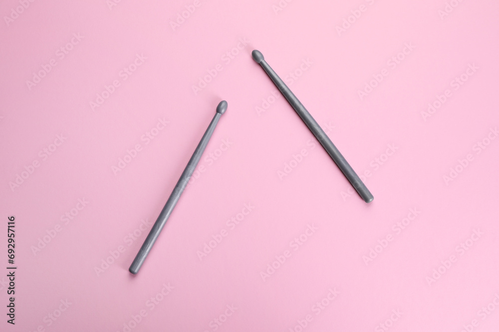 Two grey drumsticks on pink background, top view Two grey drumsticks on pink background, top view