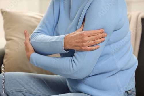 Mature woman suffering from pain in arm indoors  closeup. Rheumatism symptom