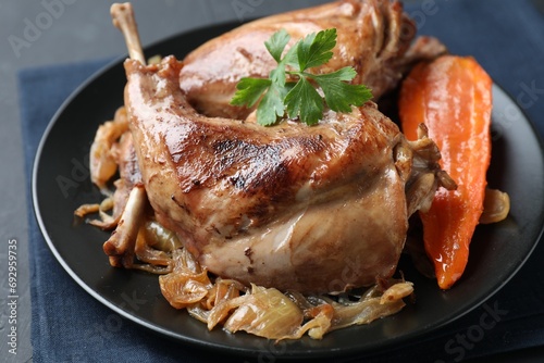 Tasty cooked rabbit meat with vegetables and parsley on table, closeup
