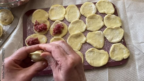 a woman makes dumplings with meat.