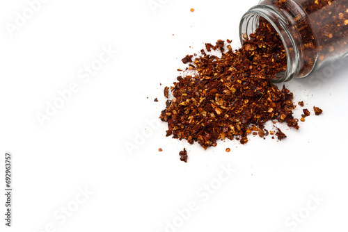 Fototapeta Naklejka Na Ścianę i Meble -  dried chili flakes spill out of glass spice jar, spice catalog concept