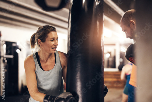 Mature woman holding a boxing gym punching bag for her partner photo