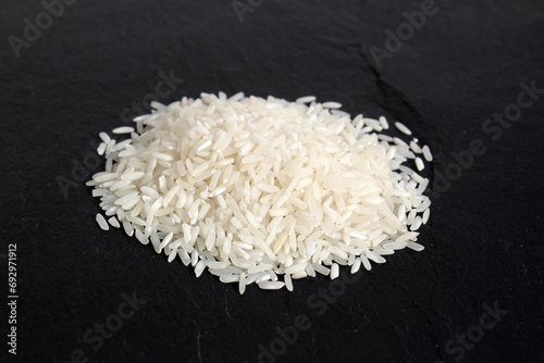 A small pile of white rice lies on a black background. 