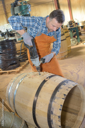 a male cooper drilling a barrel