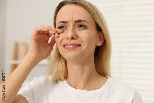 Sad woman with smeared mascara crying indoors, closeup