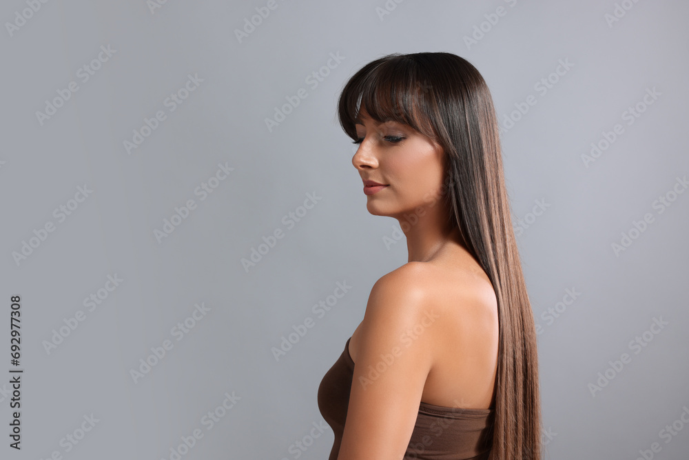 Hair styling. Beautiful woman with straight long hair on grey background, space for text Hair styling. Beautiful woman with straight long hair on grey background, space for text