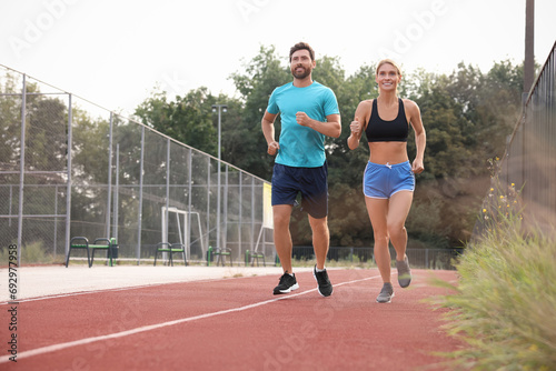 Healthy lifestyle. Happy sporty couple running at stadium, space for text © New Africa