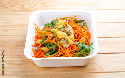 Carrot salad with orange. Healthly food. Takeaway food. On a wooden background.