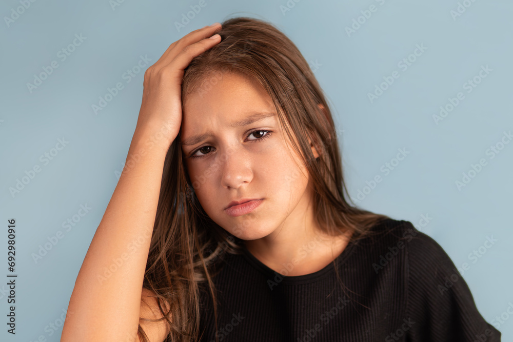 Little tired exhausted kid teen girl of 10 years old in black T-shirt put hand on forehead. look camera on pastel plain light blue background.. Little tired exhausted kid teen girl of 10 years old in black T-shirt put hand on forehead. look camera on pastel plain light blue background..