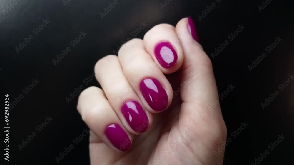 A woman shows her nails painted with bright purple gel polish. Glamorous manicure. Female right-hand fingers close-up view at the black background A woman shows her nails painted with bright purple gel polish. Glamorous manicure. Female right-hand fingers close-up view at the black background