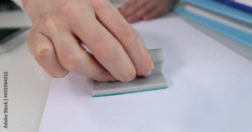 Female hands put a stamp approved on a sheet of paper, close-up. Documentation approval, slowmotion. Positive decision