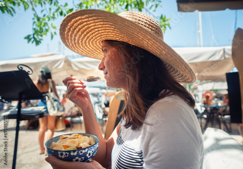 A young woman is eating a fruit salad with yogurt 