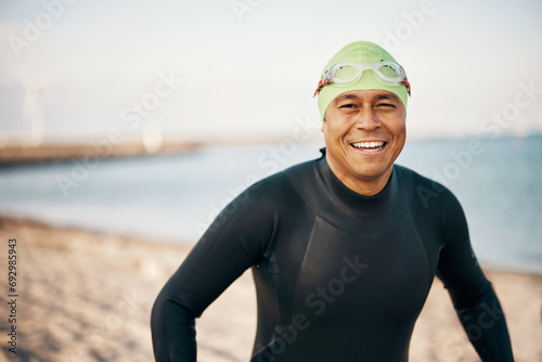 Smiling man wearing a wetsuit and goggles before an open water swim