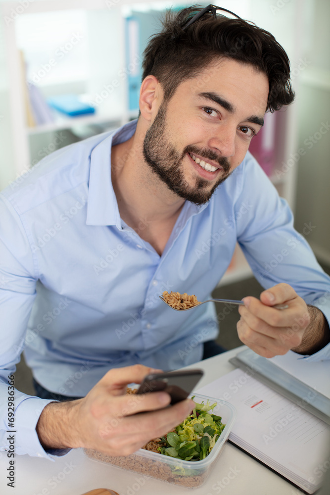 young handsome man speaks on the phone while eating salad