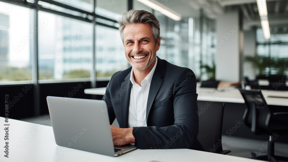 Company manager, CEO, happy middle-aged company executive working with laptop computer Company manager, CEO, happy middle-aged company executive working with laptop computer