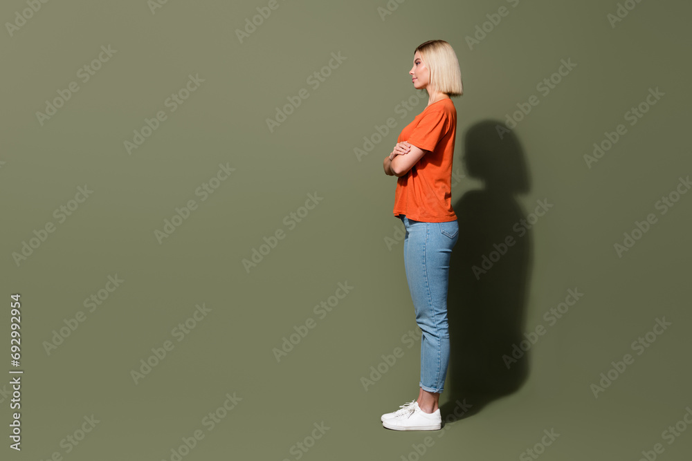 Full length photo of blonde hair model girl crossed hands confident watch empty space dealer center ad isolated on khaki color background Full length photo of blonde hair model girl crossed hands confident watch empty space dealer center ad isolated on khaki color background