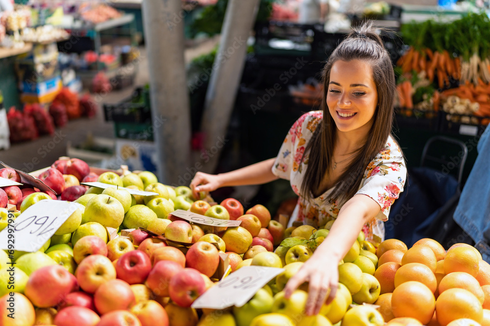 A snapshot capturing a girl with a basket in her hands, carefully selecting fruits to purchase from one of the stalls at the market. A snapshot capturing a girl with a basket in her hands, carefully selecting fruits to purchase from one of the stalls at the market.