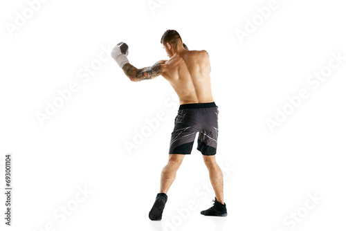 Full-length of shirtless young man with muscular strong body, boxer in motion, training isolated over white background. Concept of professional sport, combat sport, martial arts, strength © master1305