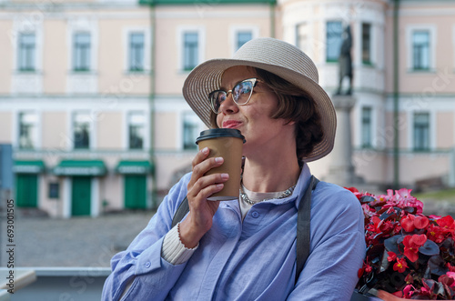A girl drinks coffee from a paper cup in a coffee shop on the street of an ancient city