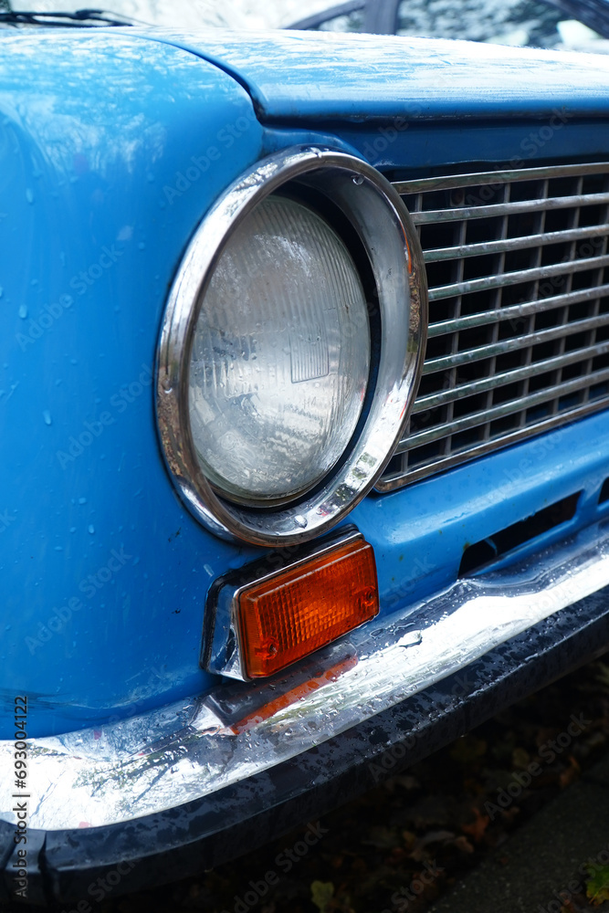 Closeup of an old light blue Russian limousine, radiator grille and chrome headlights. Classic car from the Ukraine.