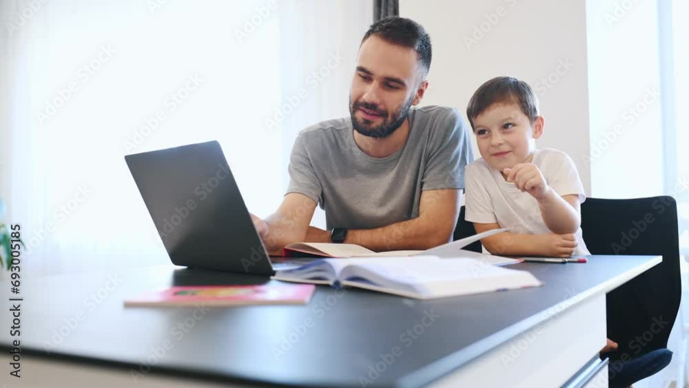 Doing homework. Father and son are at home by the table. Doing homework. Father and son are at home by the table.