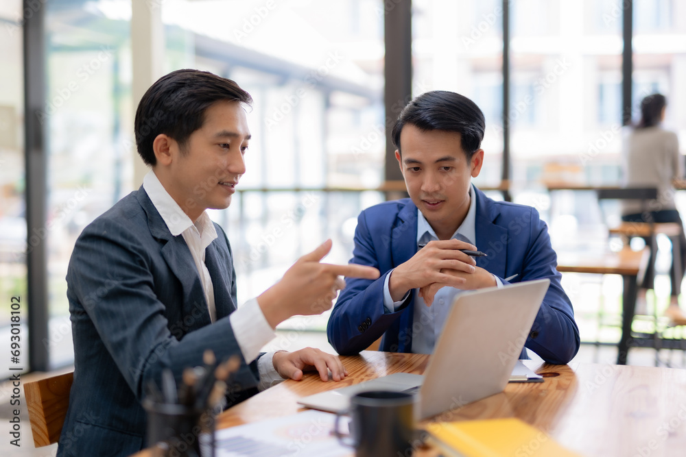 Two happy asian businessman talking and consulting working together with laptop computer in the office. Two happy asian businessman talking and consulting working together with laptop computer in the office.