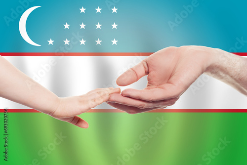 Uzbek baby and parent hands on the background of flag of Uzbekistan Help, aid, support, charity concept photo