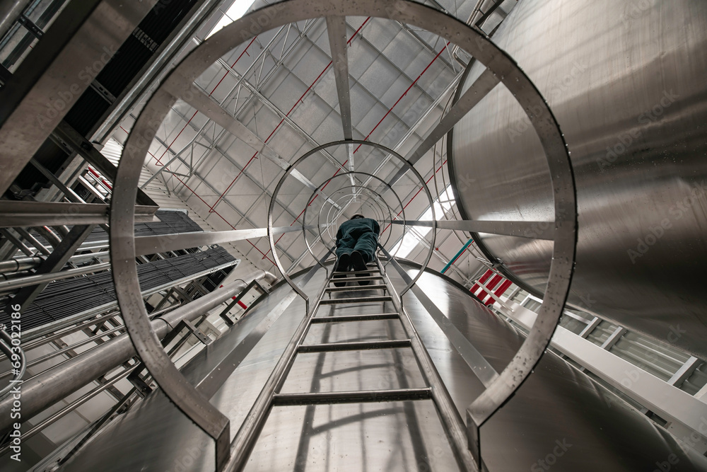 Obraz premium The male worker down the ladder is for inspection stainless steel tank chemical.