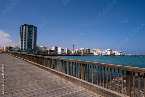 View of the city of Arrecife from the Fermina islet, from a wooden bridge. Turquoise blue water. Sky with big white clouds. Seascape. Lanzarote, Canary Islands, Spain.