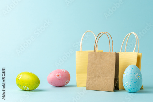 Shopping bags with Easter eggs on blue background. Creative minimal shopping concept. photo