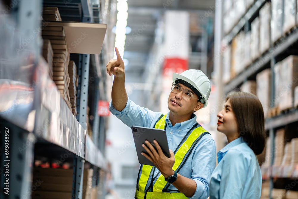 Warehouse staff working together using digital tablets to check the