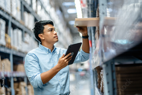 Businessman or supervisor uses a digital tablet to check the stock inventory in furniture large warehouses, a Smart warehouse management system, supply chain and logistic network technology concept. photo