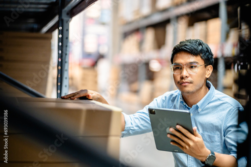 Businessman or supervisor uses a digital tablet to check the stock inventory in furniture large warehouses, a Smart warehouse management system, supply chain and logistic network technology concept.
