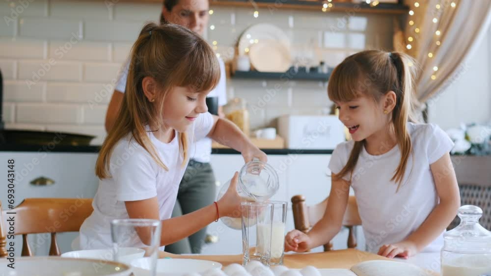 Learning how to prepare food. Mother with her little two daughters is on the kitchen with garlands. Learning how to prepare food. Mother with her little two daughters is on the kitchen with garlands.