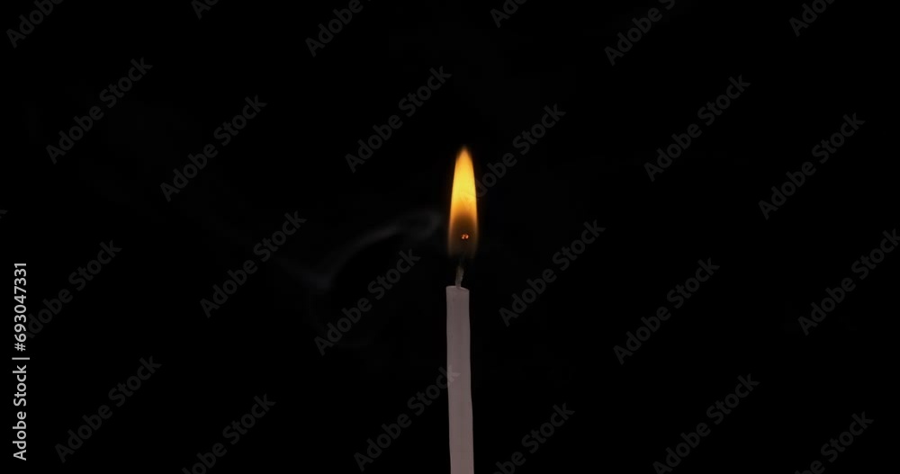 Thin burning candle backlit on a black background Thin burning candle backlit on a black background