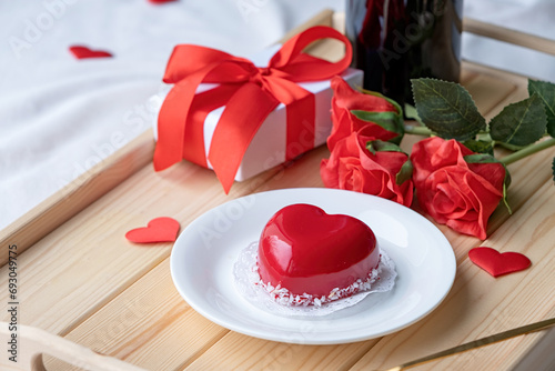 heart shaped glazed valentine cake and flowers on wooden tray