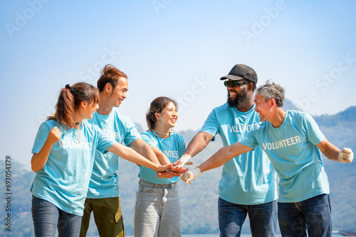 group of diverse ethnicity volunteers smiling,stacked hands together gesture of engage in some sort of teamwork activity, joining forces together to work for society