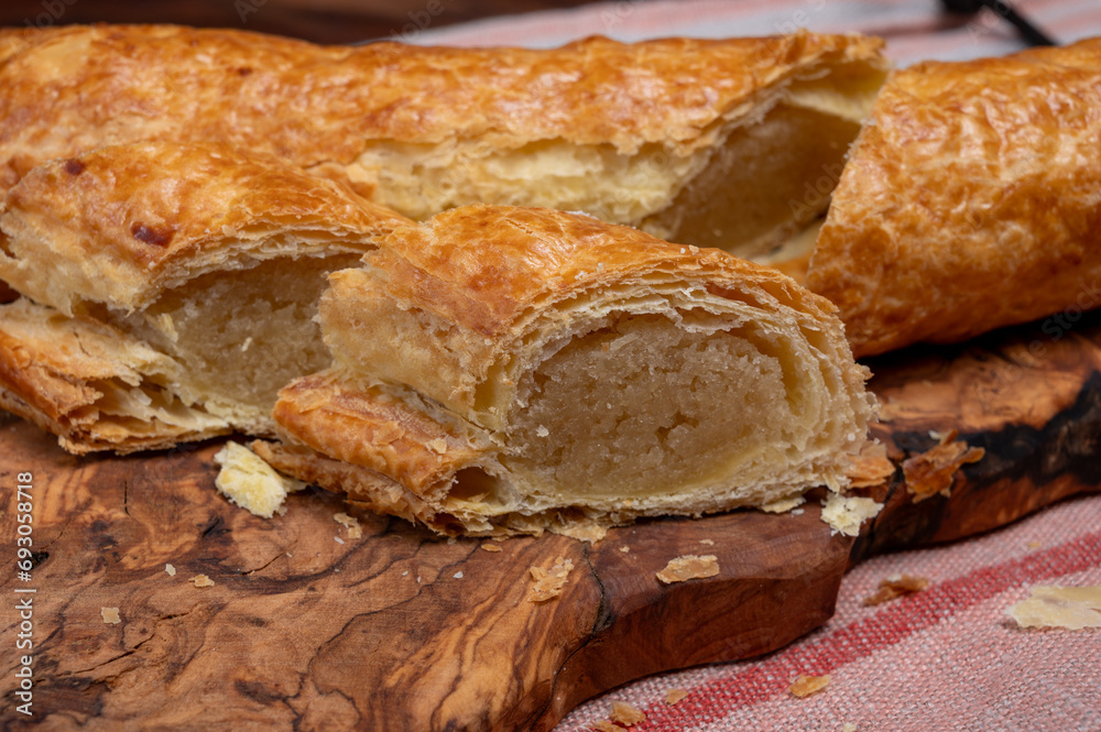 Fresh baked Dutch filled spicy cookies from puff pastry with almonds on wooden board close up